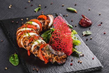 Mozzarella peyniri, domates, pesto sosu ve siyah arka planda yeşil salata ile pişmiş dana eti. Sıcak et yemekleri. Üst görünüm, düz yatıyordu.