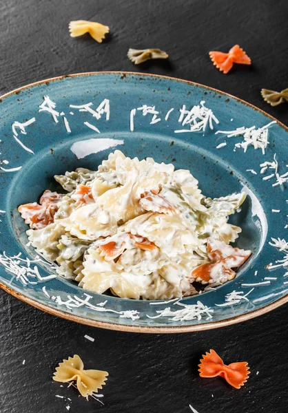 Фарфалле макароны в сливочном соусе сыра в тарелке на темном каменном фоне. Вид сверху, плоский. Вегетарианская еда . — стоковое фото