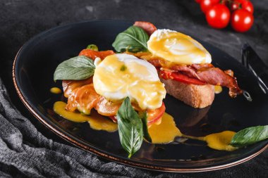 Sağlıklı kahvaltı sandviçleri. Ekmek kızarmış yumurta ya da yumurta Benedict, taze sebzeler, avokado, fileto somon, karanlık arka planda pastırma ile tost. Temiz yemek, sağlıklı gıda, diyet, seçici odak