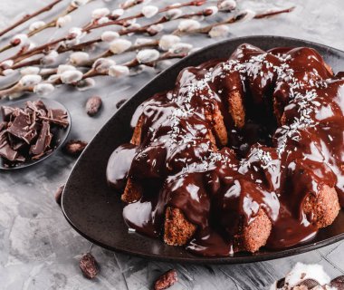 Paskalya kek çikolata, Hindistan cevizi, bir taş zemin üzerine bahar çiçekleri ile. Mutlu Paskalya kutlamaları.