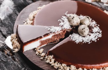 Paskalya kek ayna sır çikolata, Hindistan cevizi, bahar çiçekleri, Bıldırcın yumurta rustik arka plan üzerinde. Mutlu Paskalya kutlamaları. Üstten Görünüm, düz yatıyordu