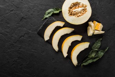 Siyah taş zemin üzerine sarı kavun. Renkli taze meyve. Üstten görünüm, düz yatıyordu, kopya alanı.