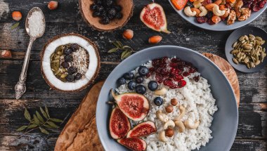 Pilav Hindistan cevizi yulaf lapası incir, çilek, fındık, Kuru kayısı ve plaka rustik ahşap zemin üzerine Hindistan cevizi sütü ile. Sağlıklı kahvaltı malzemeler. Yeme, vegan gıda kavramı temiz. Üstten görünüm