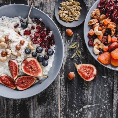 Pilav Hindistan cevizi yulaf lapası incir, çilek, fındık, Kuru kayısı ve plaka rustik ahşap zemin üzerine Hindistan cevizi sütü ile. Sağlıklı kahvaltı malzemeler. Temiz yemek, vegan gıda kavramı, üstten görünüm