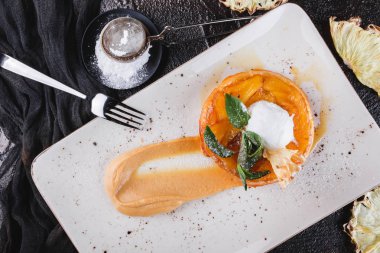 Ananas, reçel, dondurma ile lezzetli elma strudel ile kahvaltı nane ve koyu arka plan üzerinde hafif plaka üzerinde toz şeker ile süslenmiş. Puf hamur işleri, tatlı, fırın. Üst görünüm, düz yatıyordu