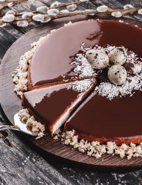 Paskalya kek ayna sır çikolata, Hindistan cevizi, bahar çiçekleri, Bıldırcın yumurta rustik arka plan üzerinde. Mutlu Paskalya kutlamaları. Üstten Görünüm, düz yatıyordu