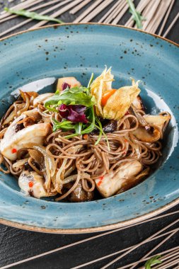 Tatlı ve ekşi sos, soğan ve plaka karanlık taş zemin üzerine yeşil yabani mantar ile soba erişte. Vejetaryen yiyecekler