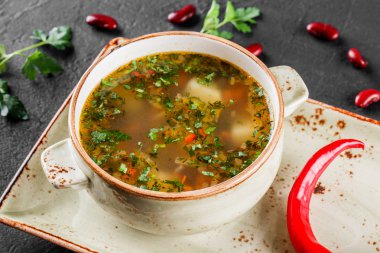 Fasulye, sebze, koyu taş arka plan tabakta otlar ile Çorba. Temiz beslenme, sağlıklı gıda konsepti. Üstte görüntü.