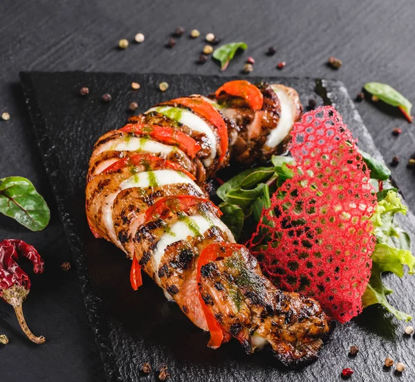 Mozzarella peyniri, domates, pesto sosu ve siyah arka planda yeşil salata ile pişmiş dana eti. Sıcak et yemekleri