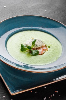 Koyu taş arka plan üzerinde tabakta karides ve peynir ile Brokoli yeşil krema çorbası. Temiz beslenme, sağlıklı gıda konsepti. Üstte görüntü.