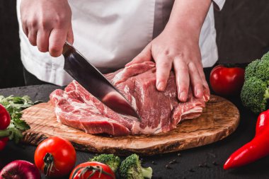 Şef Kasap mutfakta bıçakla domuz eti kesiyor, yemek pişiriyor..