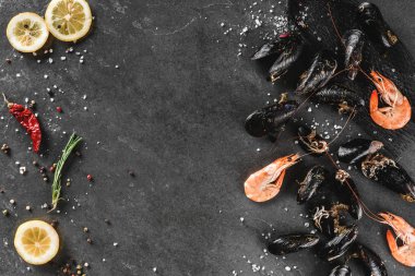 Taze çiğ midye ve koyu taş arka plan üzerinde baharat ile karides. Deniz ürünleri, üst görünüm, düz yatıyordu, kopyalama alanı.