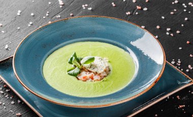 Koyu taş arka plan üzerinde tabakta karides ve peynir ile Brokoli yeşil krema çorbası. Temiz beslenme, sağlıklı gıda konsepti. Üstte görüntü.