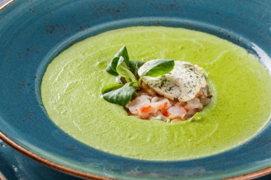 Koyu taş arka plan üzerinde tabakta karides ve peynir ile Brokoli yeşil krema çorbası. Temiz beslenme, sağlıklı gıda konsepti. Üstte görüntü.