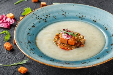 Kereviz tartare üzerinden pişmiş sebze ile krem çorba kruton ve roka plaka karanlık taş zemin üzerine dekore edilmiştir. Üstten Görünüm, düz yatıyordu. Vejetaryen yiyecekler