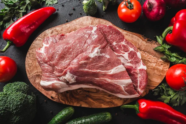 Syrové maso, hovězí steak na řezací desce přes černé pozadí s ingrediencemi pro vaření. Pohled shora. — Stock fotografie