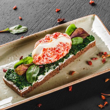 Sağlıklı kahvaltısandviçleri. Bruschetta haşlanmış yumurta veya yumurta Benedict, taze sebze, koyu arka plan üzerinde ıspanak ile. Temiz beslenme, sağlıklı gıda, diyet, üst görünümü.