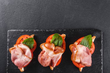 Meze bruschetta salam, jambon, domates ve baharat siyah şeyl üzerinde siyah taş zemin kurulu. Sağlıklı gıda kavramı, üstten görünüm, düz yatıyordu
