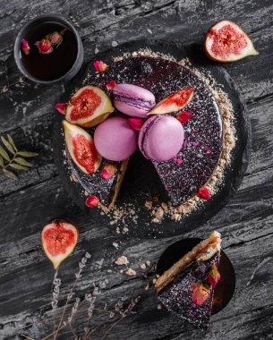 Aynalı kremalı çikolatalı pasta. Makaronlarla, incirlerle, koyu kırsal arka planda çiçeklerle süslenmiş. Tatil pastası kutlaması. Üst manzara, düz uzanma.