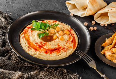 Zeytinyağı ile Nohut humus, koyu bir tabakta kırmızı biber