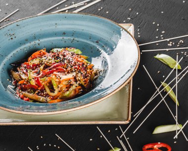 Soslu makarna spagetti, güveç sebze ve tabakta tohumlar