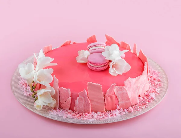 マカロンで装飾された鏡釉のピンクムースケーキ、ピンクの休日の背景に幸せな誕生日のための花。ホリデーケーキのお祝い、終わり — ストック写真