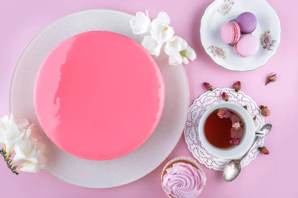 マカロンで装飾された鏡釉のピンクムースケーキ、ピンクの休日の背景に幸せな誕生日のための花。お祝いのケーキよ。トップビュー、フラットレイアウト — ストック写真