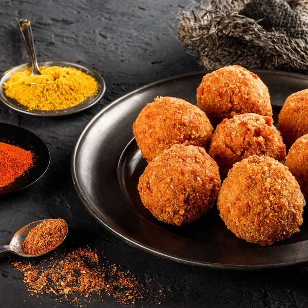 Bolas de queso de patata frita o croquetas con especias en plato negro sobre fondo de piedra oscura. Comida poco saludable, vista superior . —  Fotos de Stock