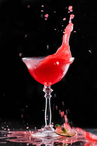 Cold red cocktail with fruit in tall glass on black background. — Stock Photo, Image