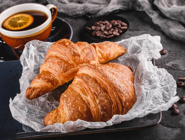 Frukost med färska franska chokladcroissanter på papper — Stockfoto