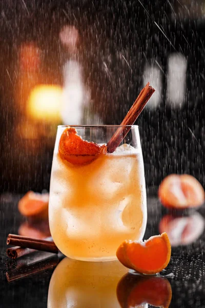 Fresh orange drink with cinnamon, tangerines and ice in glass
