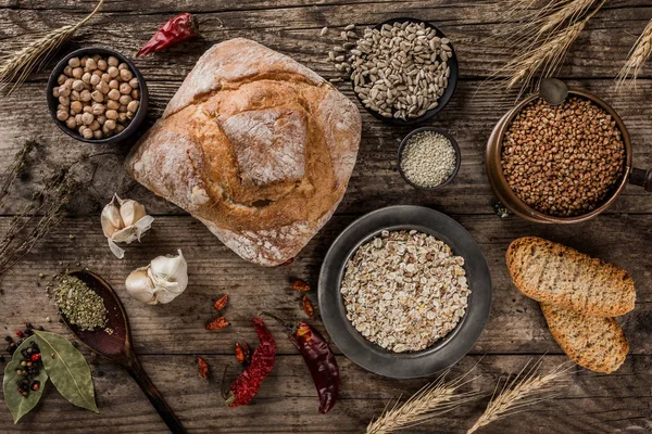 Čerstvý chléb, koření a obiloviny v miskách na rustikálním dřevě — Stock fotografie