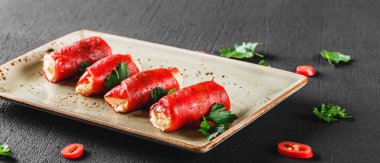 Peynir ve ekşi krema koyu taş zemin üzerine rulo fırında biber dolması. Temiz Yeme Vejetaryen yiyecekler.