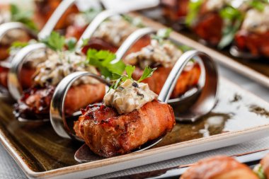 Ziyafet masasında tabakta prosciutto, krem peynir ve yeşillikli et ruloları. Catering gıda, kanepe ve aperatifler.