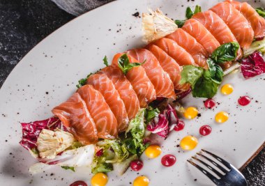 Koyu gri arka plan üzerinde plaka marul, lahana ve sos ile dilimlenmiş somon fileto Salatası. Sağlıklı yemek, temiz beslenme, diyet, yakın çekim.