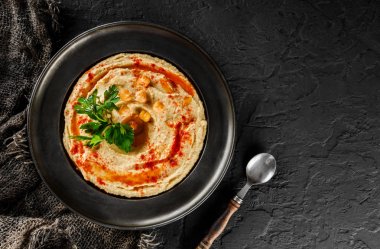 Zeytinyağı ile Nohut humus, koyu taş arka plan üzerinde bir tabak ta kırmızı biber. Sağlıklı vegan gıda, temiz beslenme, diyet, üst görünümü