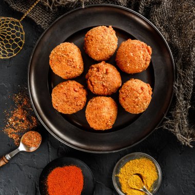 Kızarmış patates peynir topları veya taş koyu arka plan üzerinde siyah plaka üzerinde baharatlar ile kroket. Sağlıksız yiyecek, üstten görünüm