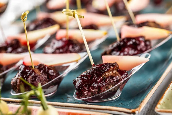 Grillad kött filé kanapéer med bakad päron och bärsås i sked på bankettbord. Matservering, förrätt tallrik och tilltugg — Stockfoto