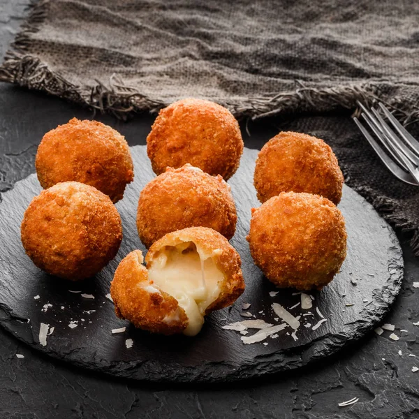 Bolas de queso de patata frita o croquetas con especias en plato negro sobre fondo de piedra oscura. Comida poco saludable, vista superior . —  Fotos de Stock
