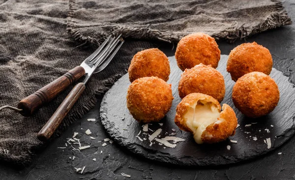 Bolas de queso de patata frita o croquetas con especias en plato negro sobre fondo de piedra oscura. Comida poco saludable, vista superior . — Foto de Stock
