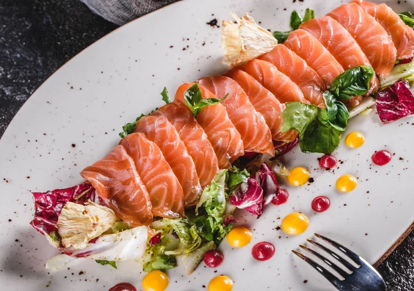 Salade de filet de saumon tranché avec laitue, chou et sauce dans une assiette sur fond gris foncé. Alimentation saine, alimentation saine, régime alimentaire, gros plan . — Photo