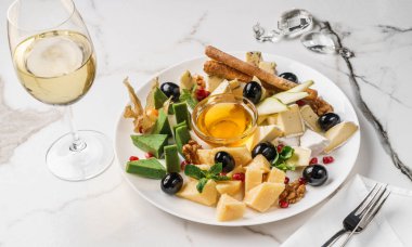 Peynir tabağı hafif mermer arka plan üzerinde şarap, fındık ve bal ile servis edilir. Aperatifler ve Şarap mezeseti, üst görünüm, düz yatıyordu.