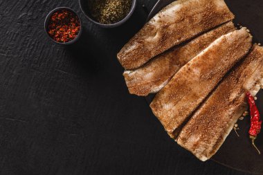 Salamura edilmiş fileto fileto ya da fileto fileto balığı baharat, yeşillik ve tabakta bir dilim ekmek ile koyu taş zemin üzerinde. Akdeniz yemekleri, aperatifler, deniz ürünleri, üst manzara.