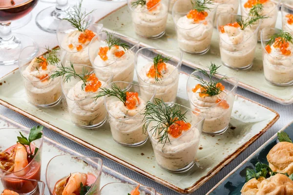 Deliciosos aperitivos con caviar rojo, camarones y mousse de queso en copas de vidrio en la mesa del banquete. Comida gourmet de cerca, snack, antipasti, plato de mariscos — Foto de Stock