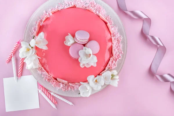 Różowy mus ciasto z lustrem glazury ozdobione makaroniki, kwiaty na urodziny na różowym tle wakacje. Świętowanie tortu. Widok z góry, płaski — Zdjęcie stockowe