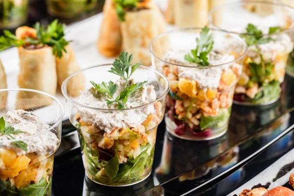 Läckra aptit retare med lax, räkor, ost och greener i glas koppar på bankett bord. Gourmetmat närbild, mellanmål, antipasti, skaldjurs tallrik. — Stockfoto