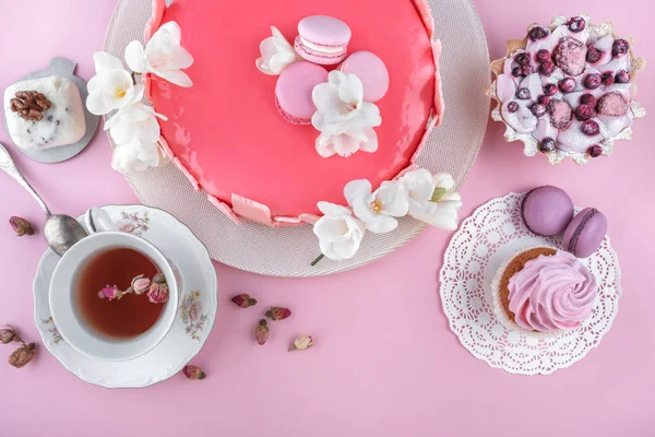 マカロンで装飾された鏡釉のピンクムースケーキ、ピンクの休日の背景に幸せな誕生日のための花。お祝いのケーキよ。トップビュー、フラットレイアウト — ストック写真