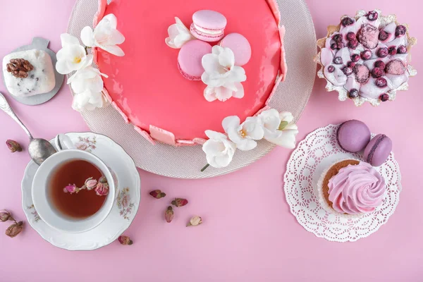 Makaronlarla süslenmiş ayna jöleli pembe kremalı pasta, pembe tatil arka planında Mutlu Yıllar için çiçekler. Tatil pastası kutlaması. Üst manzara, düz uzanma — Stok fotoğraf