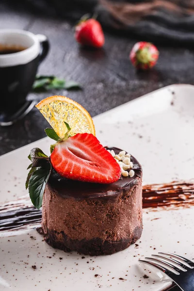 Läcker chokladcheesecake med jordgubb och mynta på tallrik över grå bakgrund. — Stockfoto