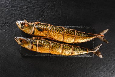 Kayrak taşı arka planda iki füme uskumru balığı. Mediterranea